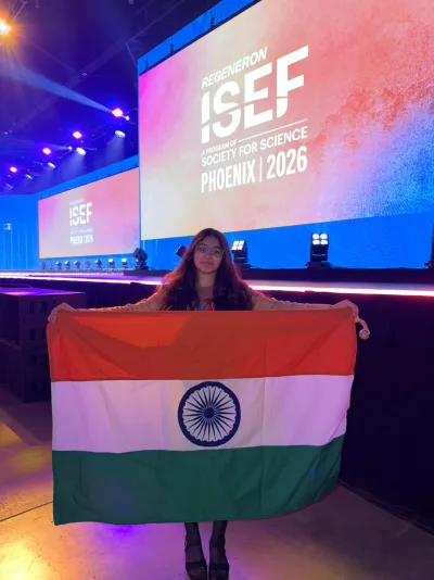 Suhani Gupta holding the Indian flag in front of the Regeneron ISEF Phoenix 2026 stage